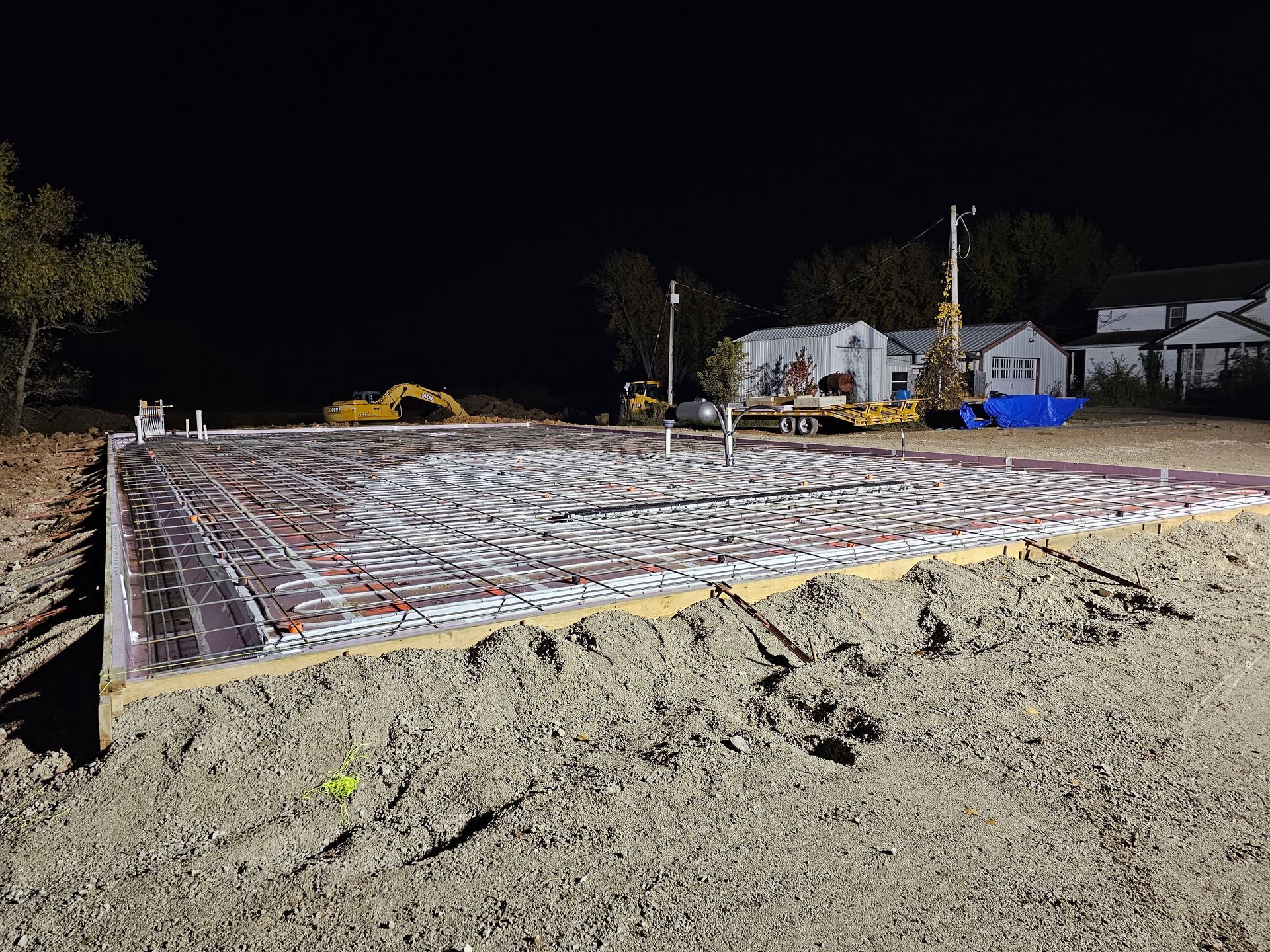 A construction site at night with a house in the background.