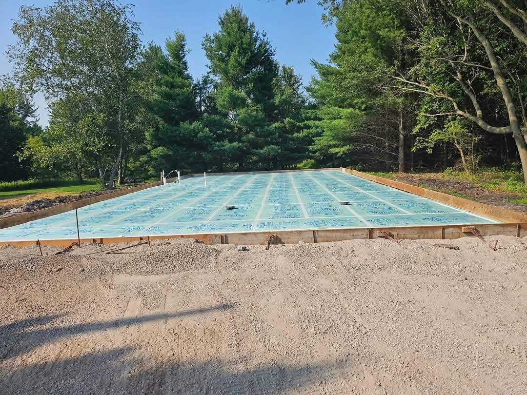 A concrete foundation is being built in a yard with trees in the background.