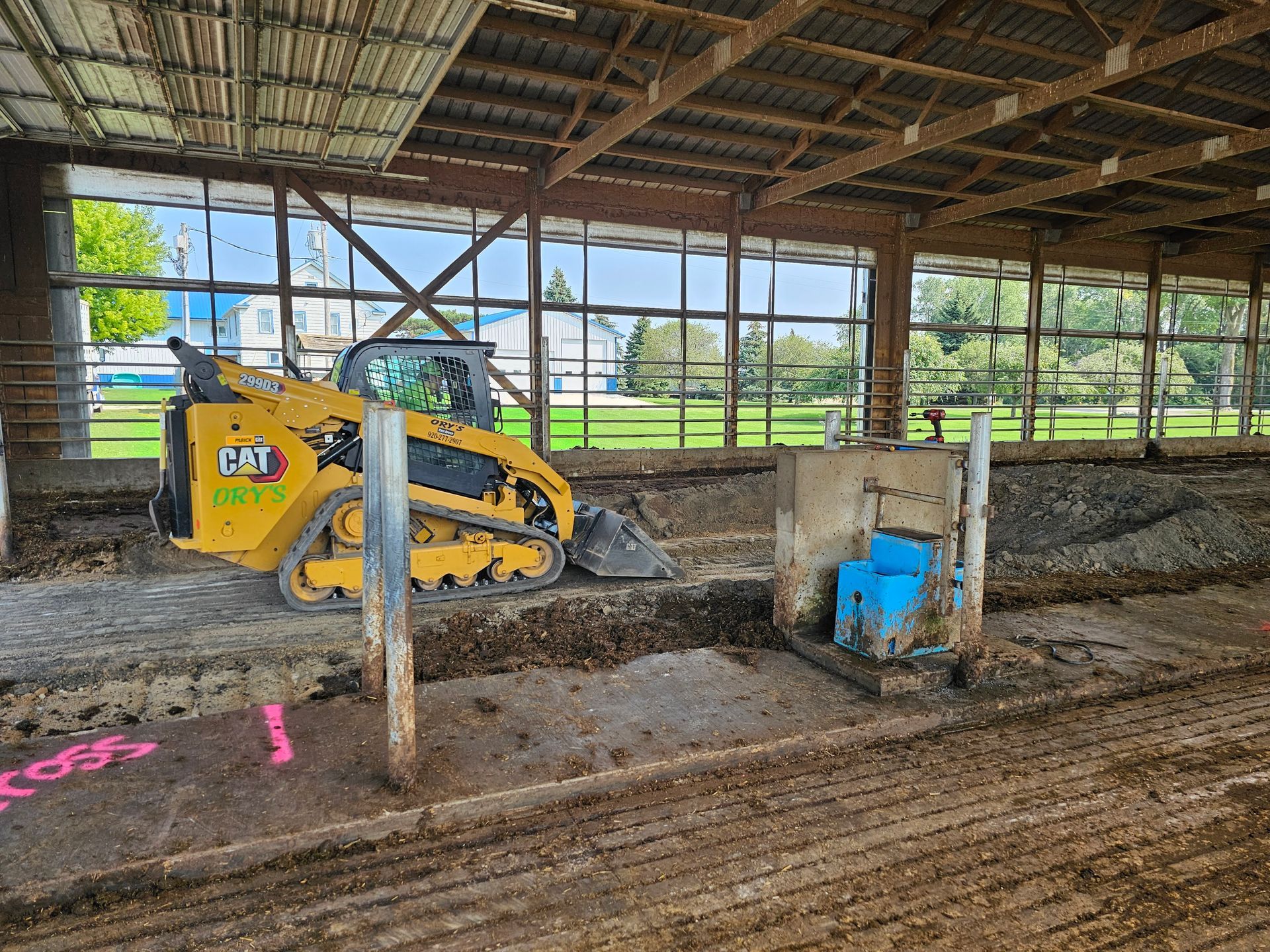 A yellow bulldozer is parked inside of a barn.