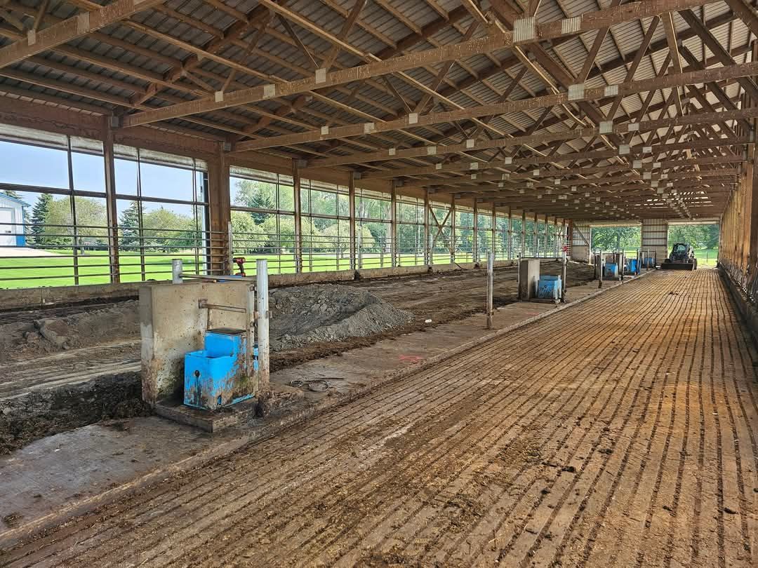 A large empty barn with a lot of windows and a tractor in the background.