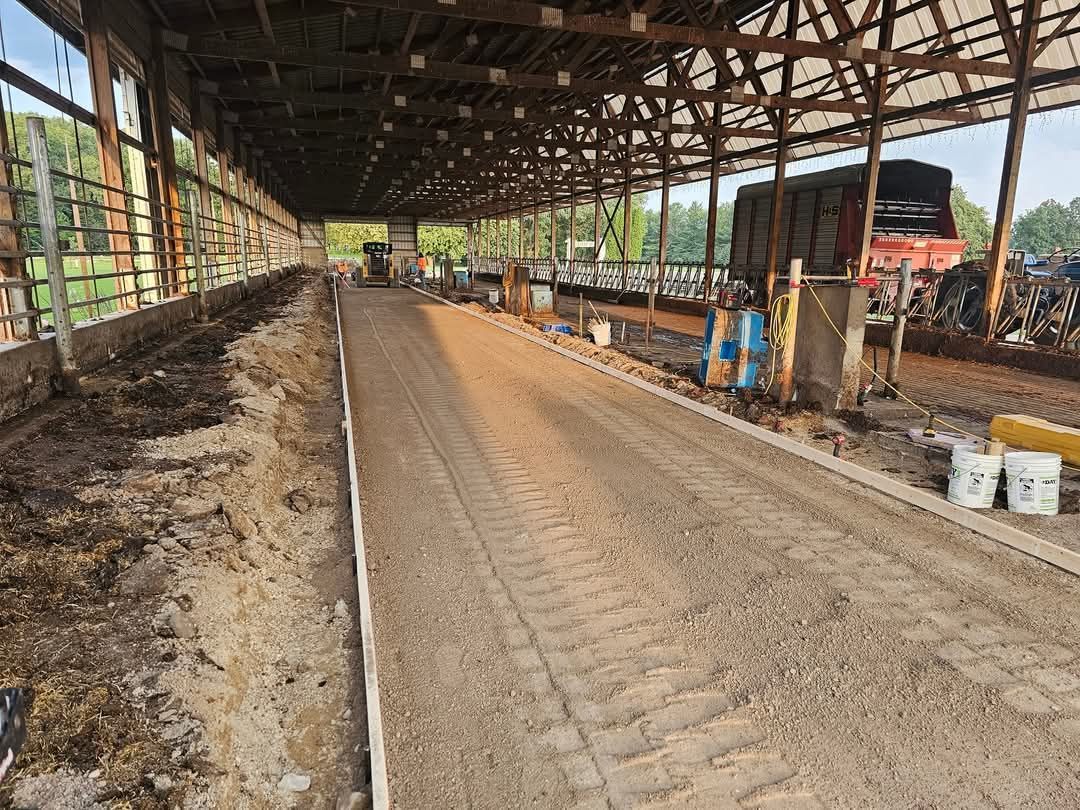 A dirt road in a barn with a tractor in the background.
