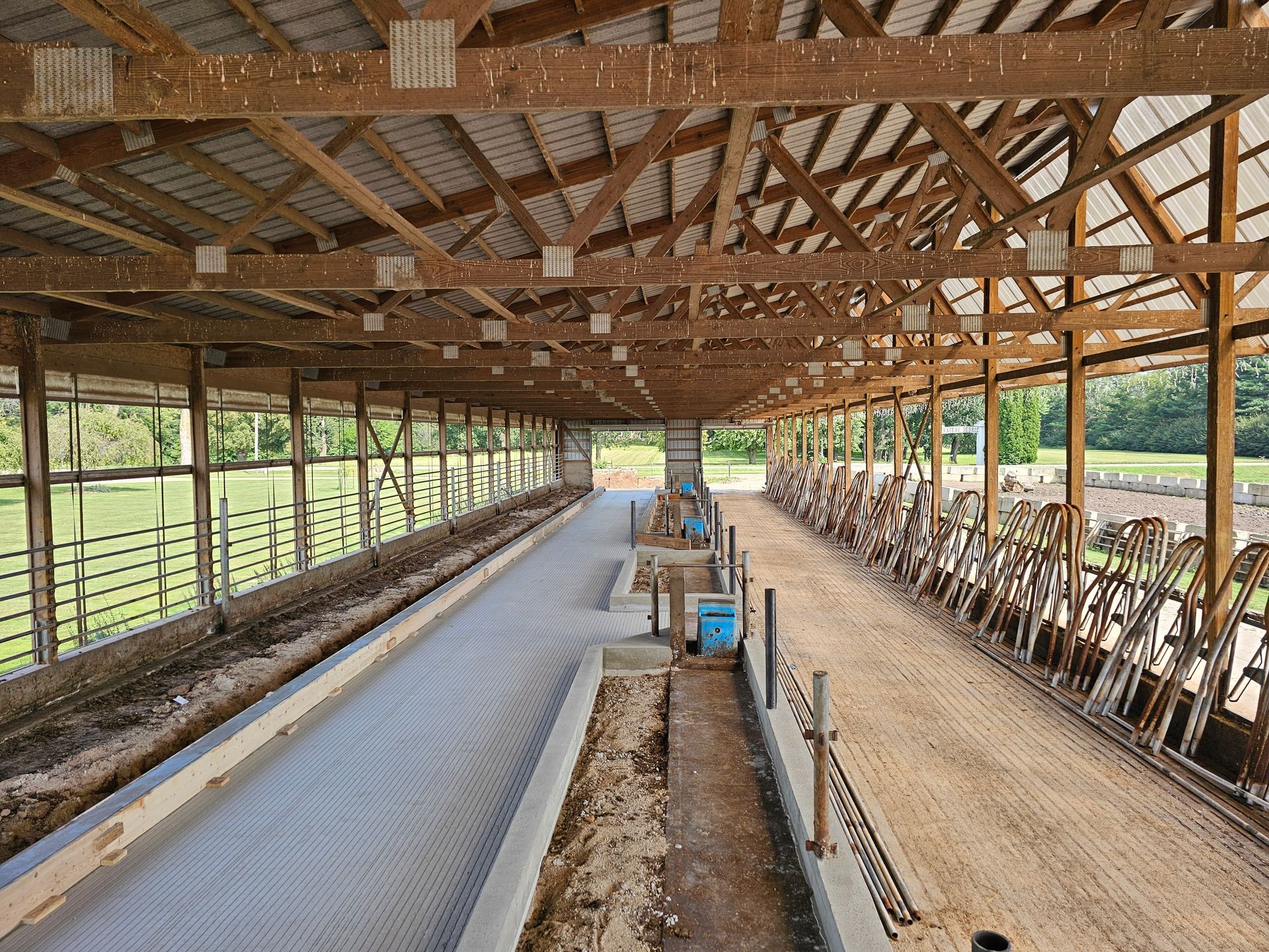 A large barn with a lot of cows inside of it.