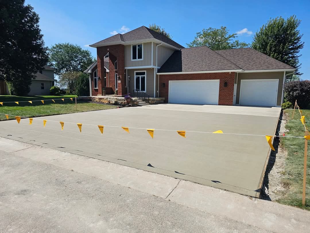 A brick house with a concrete driveway in front of it.