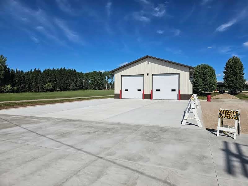 A large building with two garage doors and a concrete driveway in front of it.