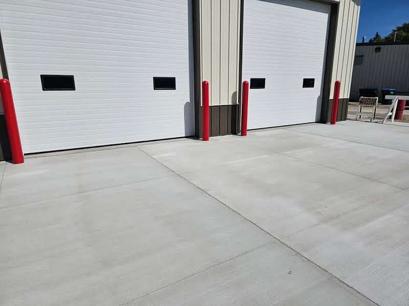 A row of white garage doors with red poles in front of them.