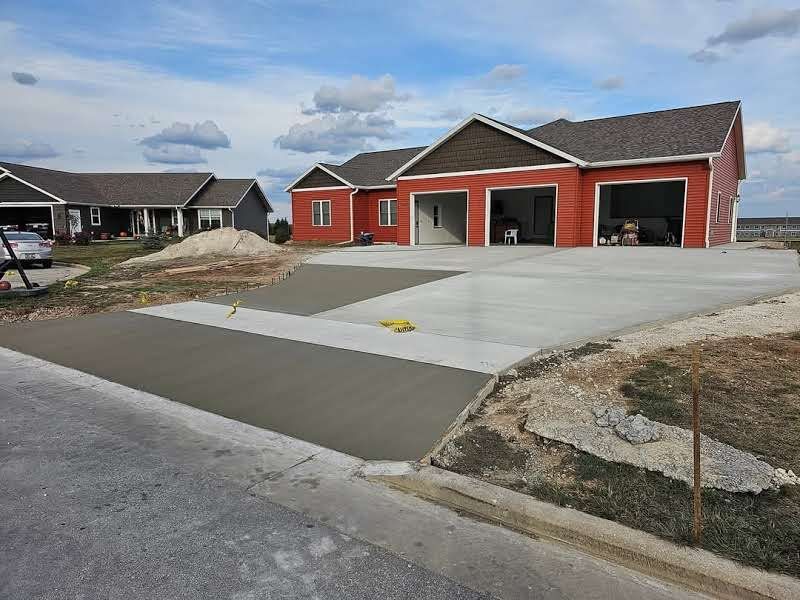 A red house with a concrete driveway in front of it.