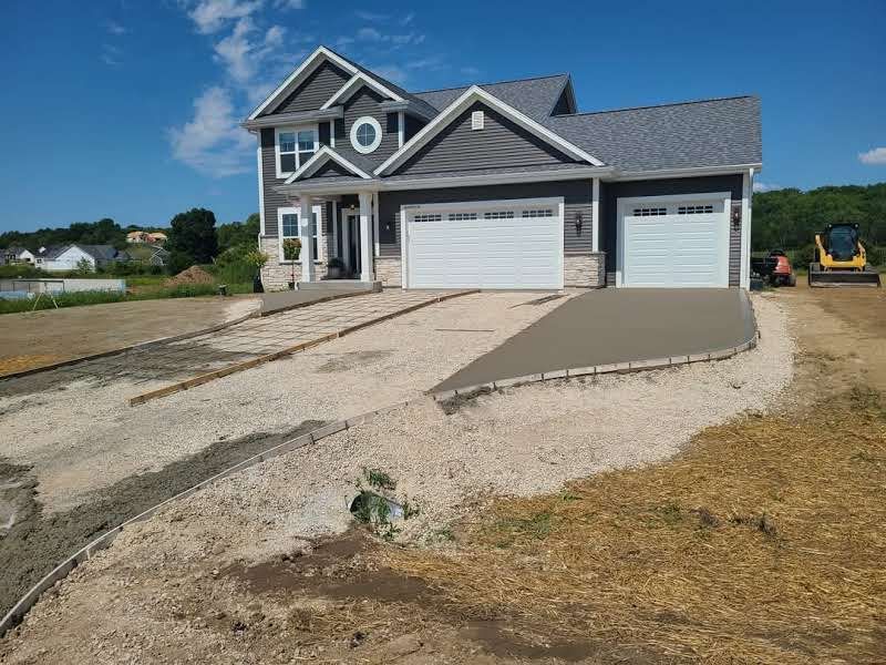 A house with two garage doors and a concrete driveway in front of it.