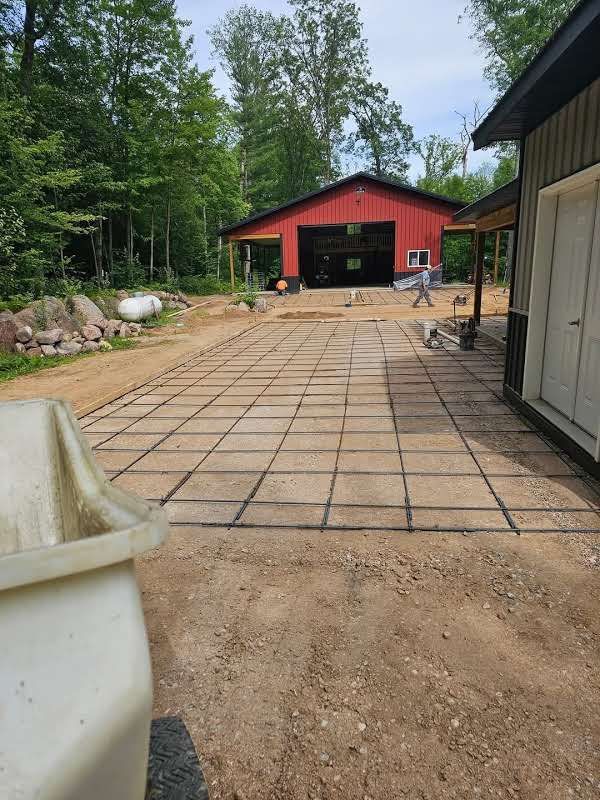 A concrete driveway is being built in front of a red barn.
