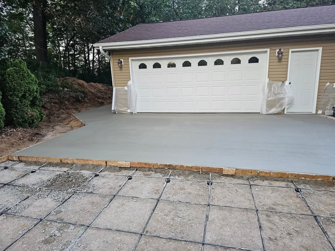 A concrete driveway is being built in front of a garage.