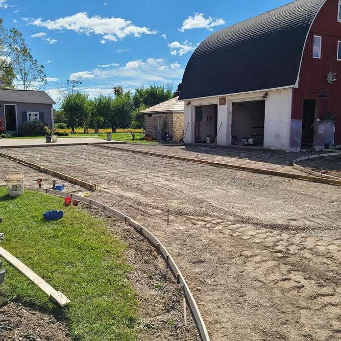 A barn with a concrete driveway in front of it
