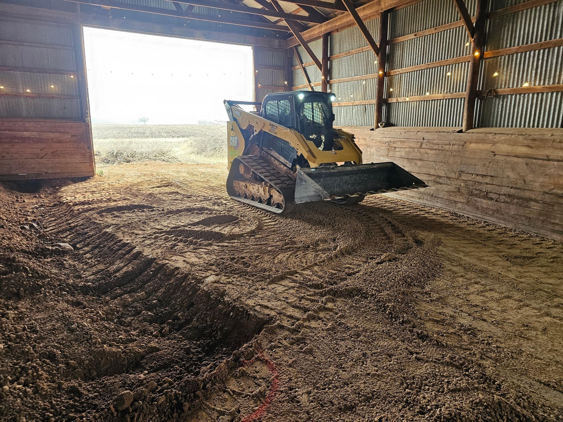 A bulldozer is moving dirt in a barn.