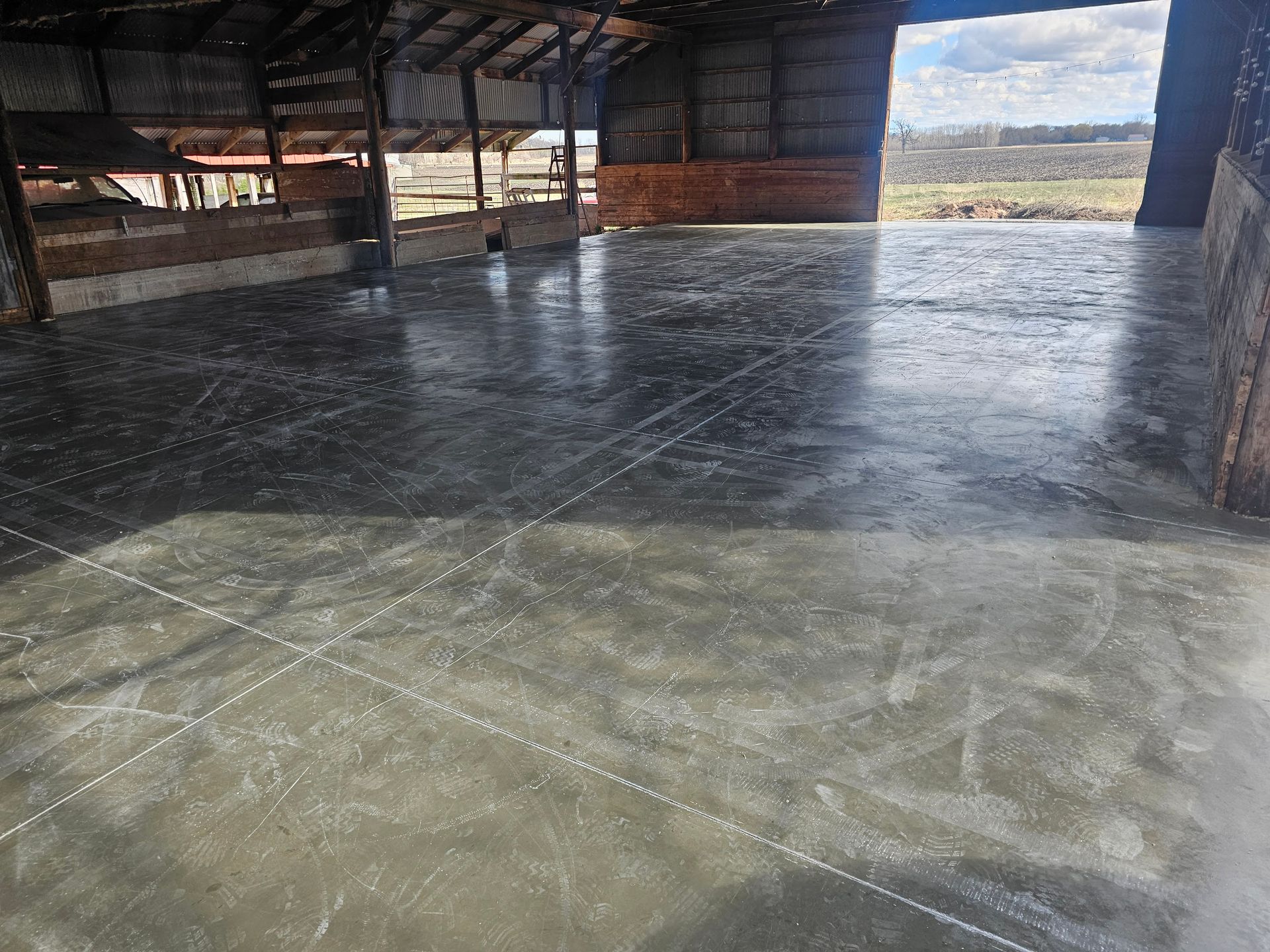 The inside of a barn with a concrete floor and a wooden roof.