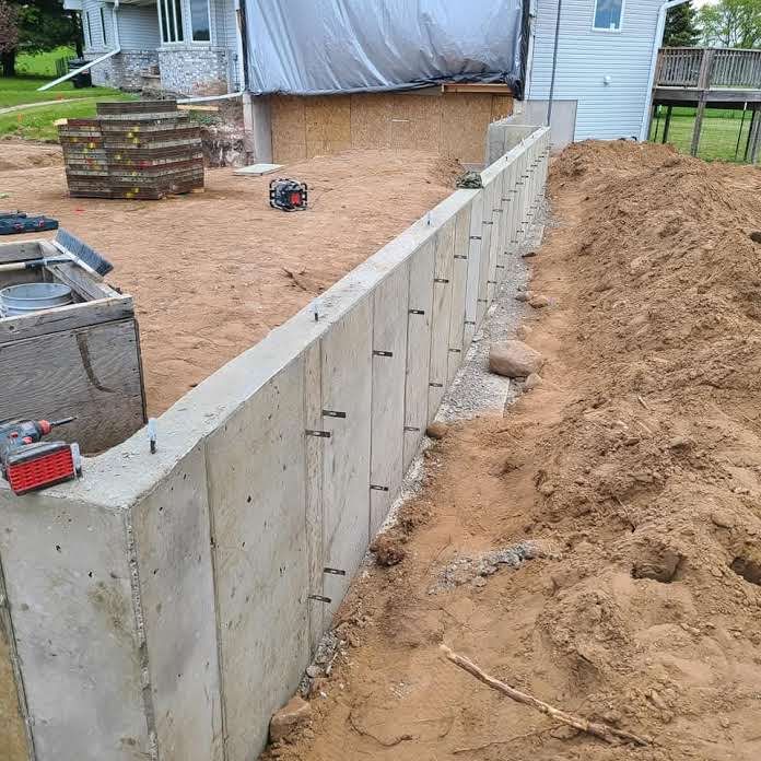 A concrete wall is being built in front of a house.