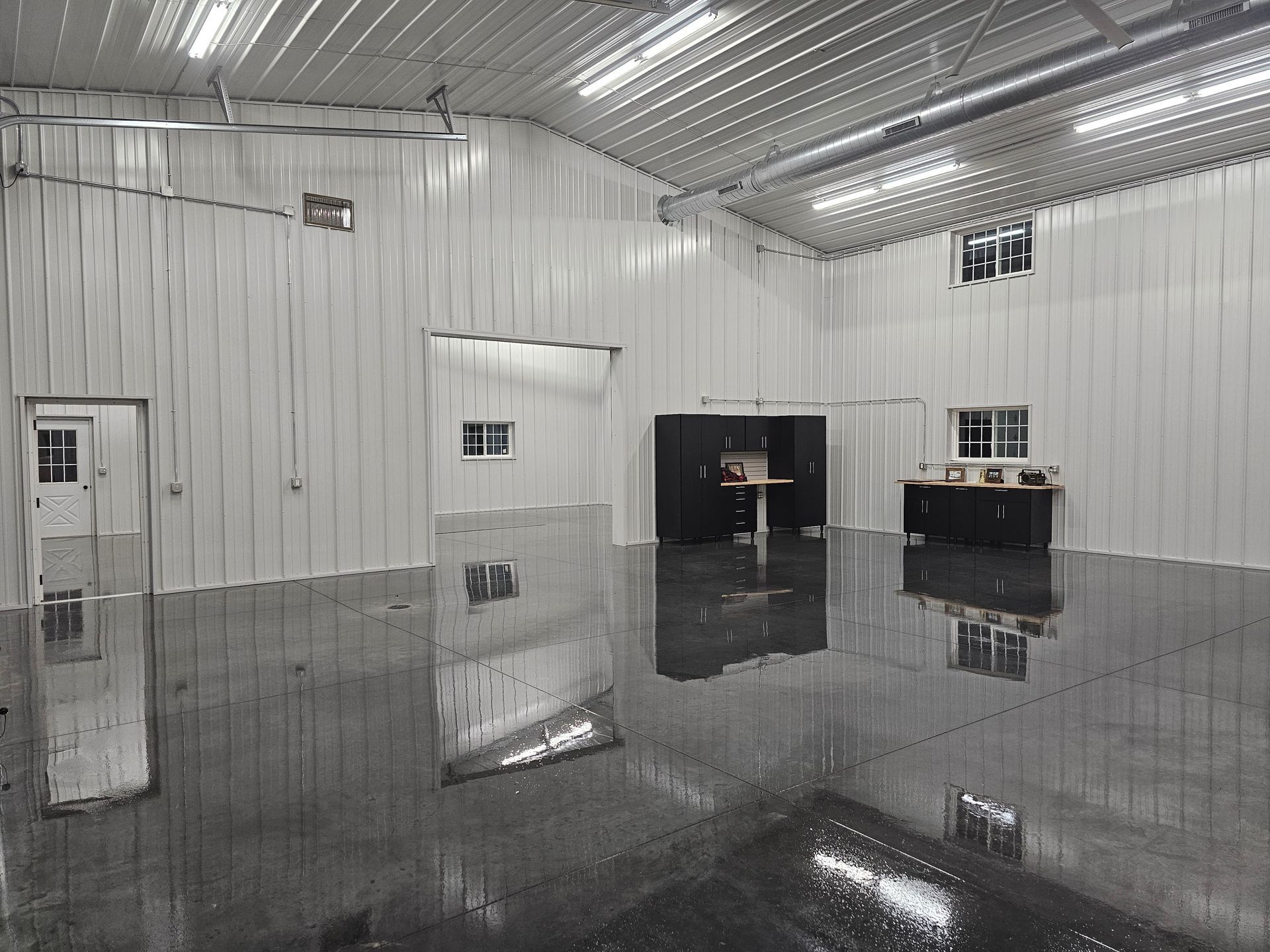 A large empty garage with a black floor and white walls.