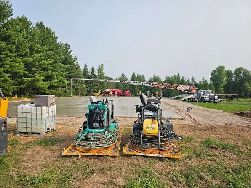 Two concrete grinders are sitting on a pallet in a field.