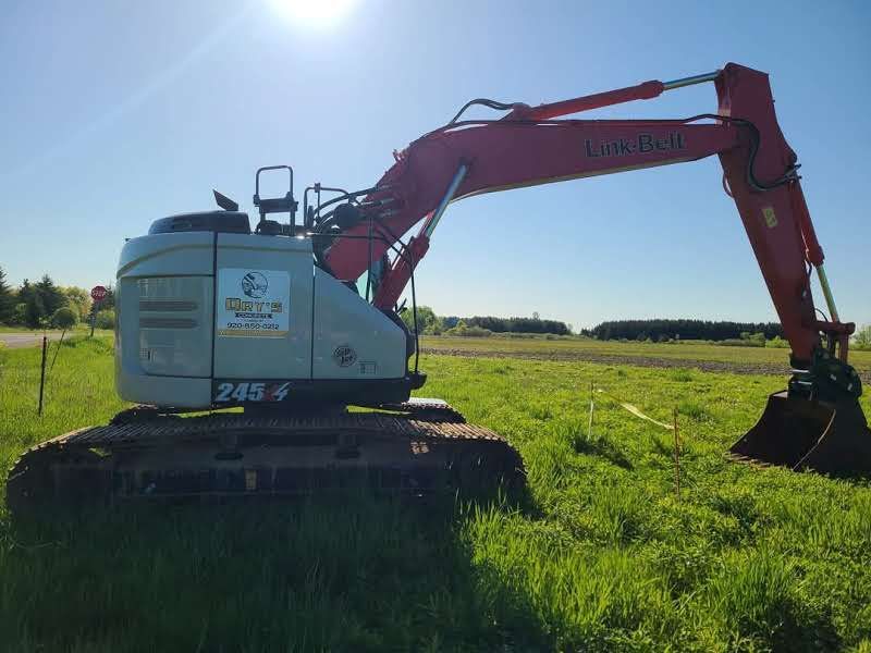 A large excavator is parked in a grassy field.