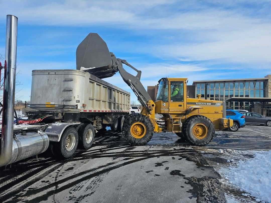 A dump truck is being loaded with dirt by a bulldozer.
