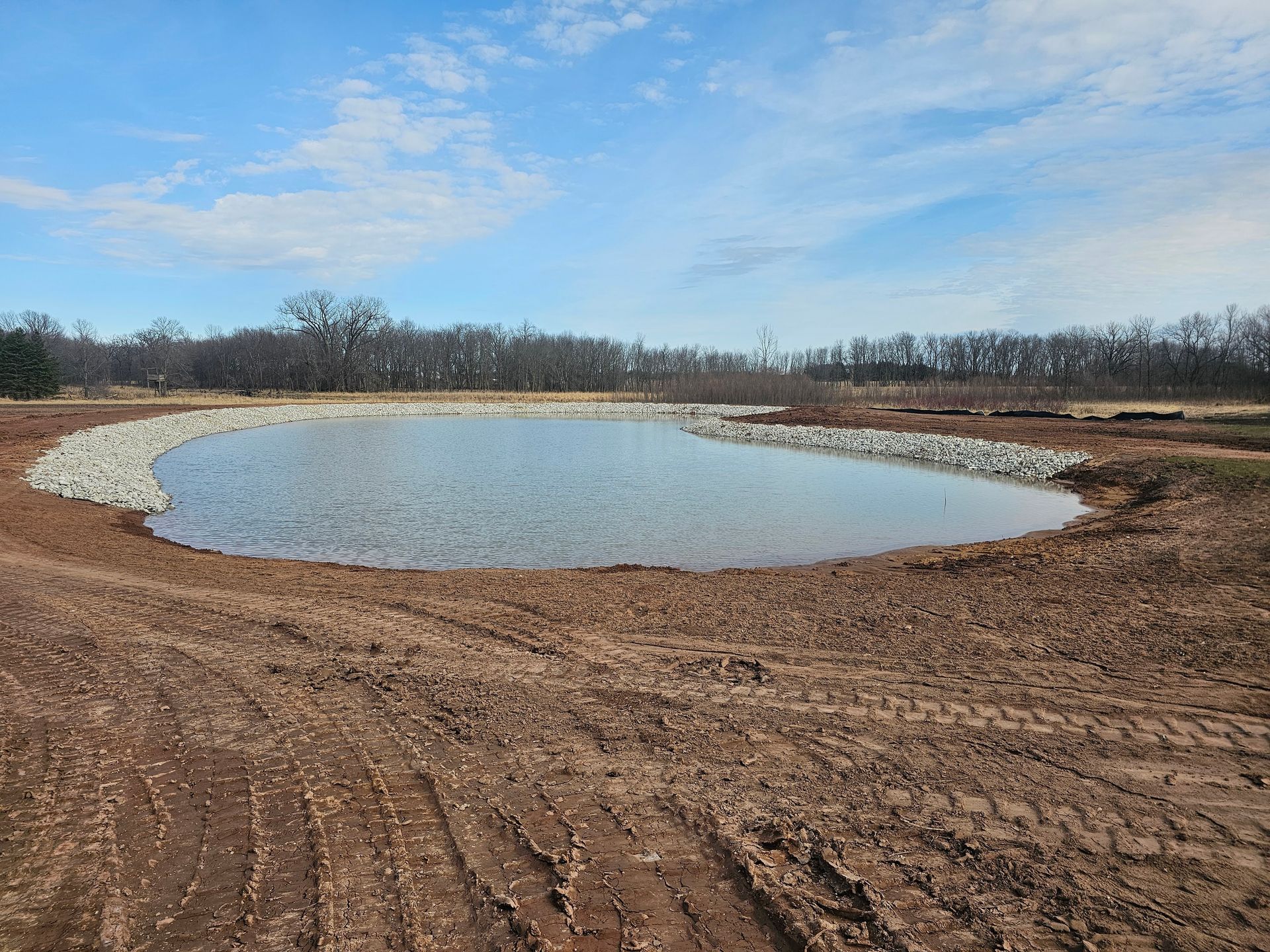 A small pond in the middle of a dirt field.
