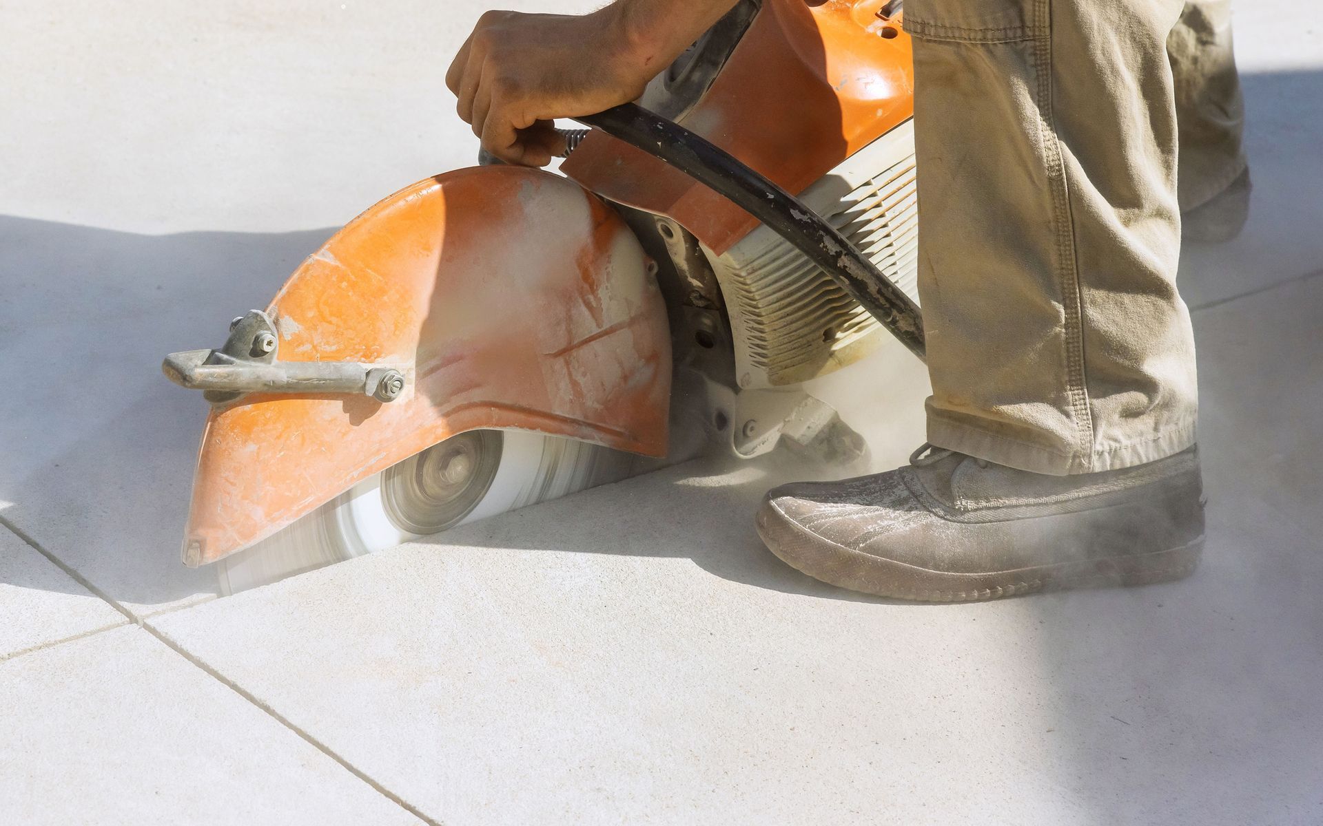 A man is using a concrete saw to cut a concrete floor