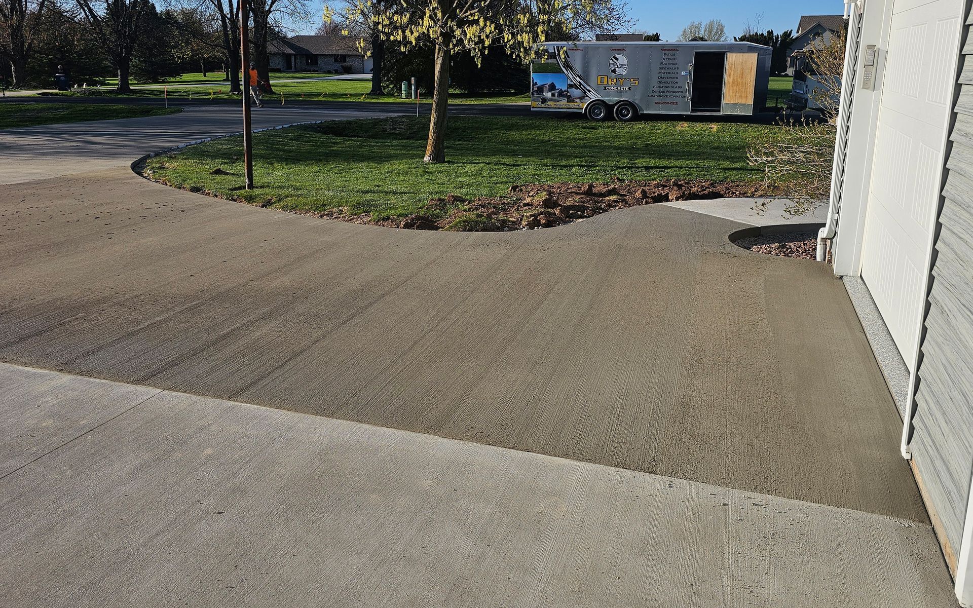 A trailer is parked in a driveway next to a house.