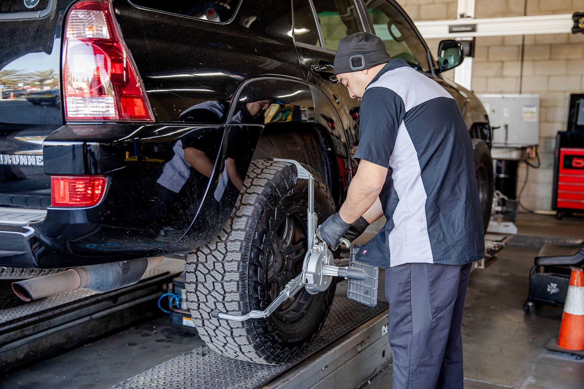 Mechanic working on a black SUV in a garage, fitting a chain on the rear wheel.