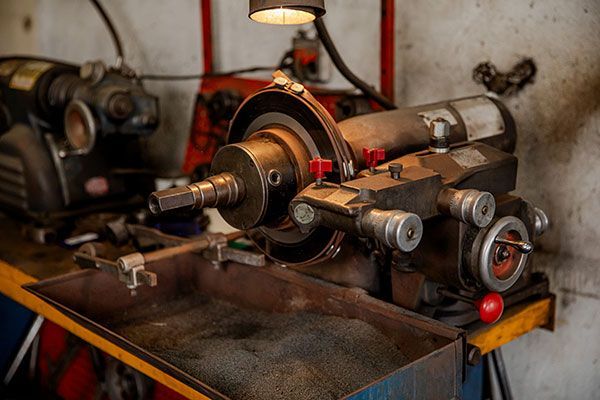 Vintage metal lathe in a workshop, with bronze and steel components on a worn workbench.