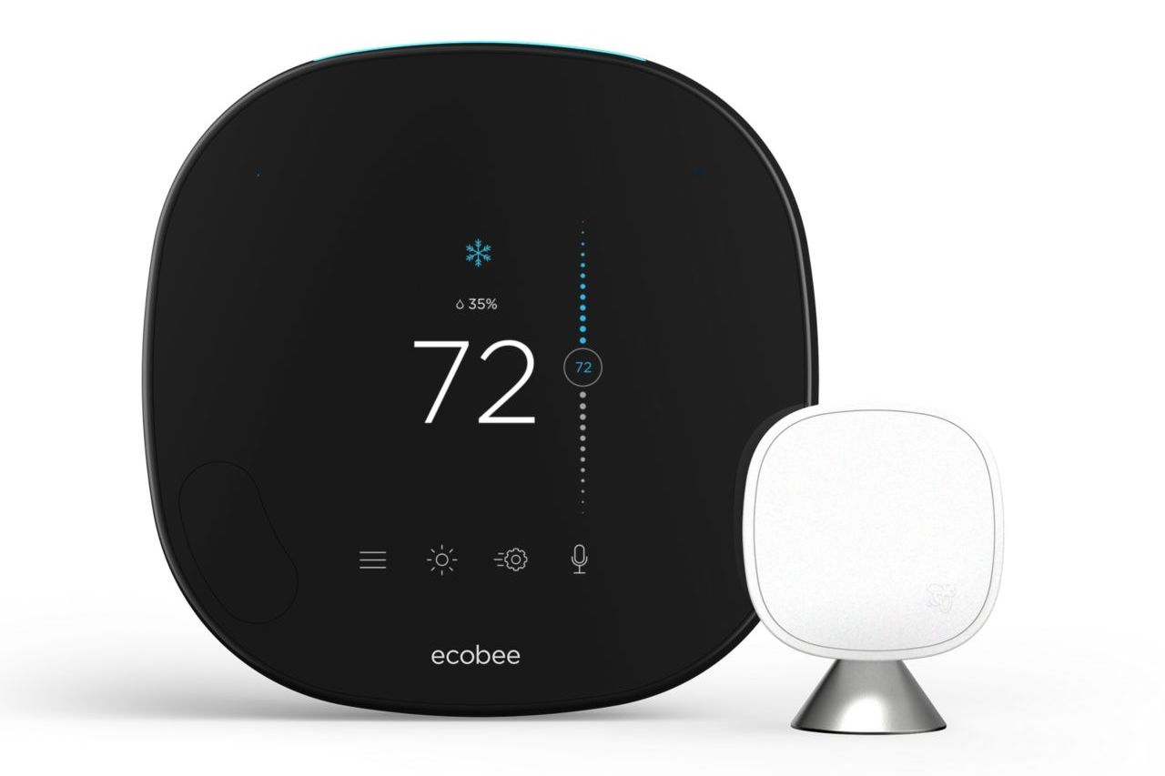 A black thermostat is sitting next to a white thermostat.