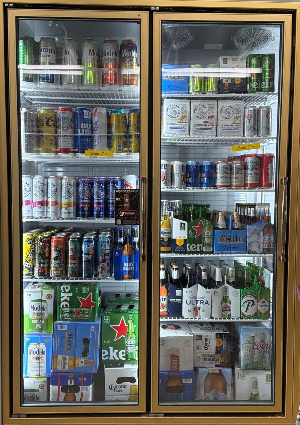 Glass-door beverage cooler stocked with assorted drinks and beers, including Heineken, in a store.