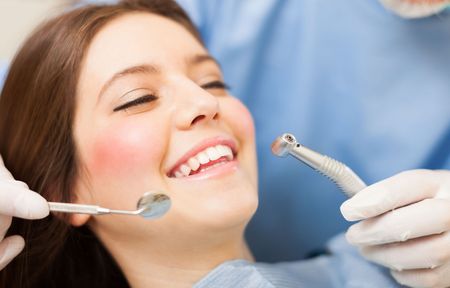 a woman is getting her teeth examined by a dentist