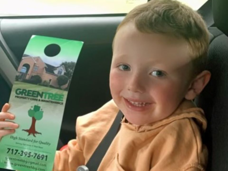 A boy holding a Green Tree Property Care & Maintenance leaflet