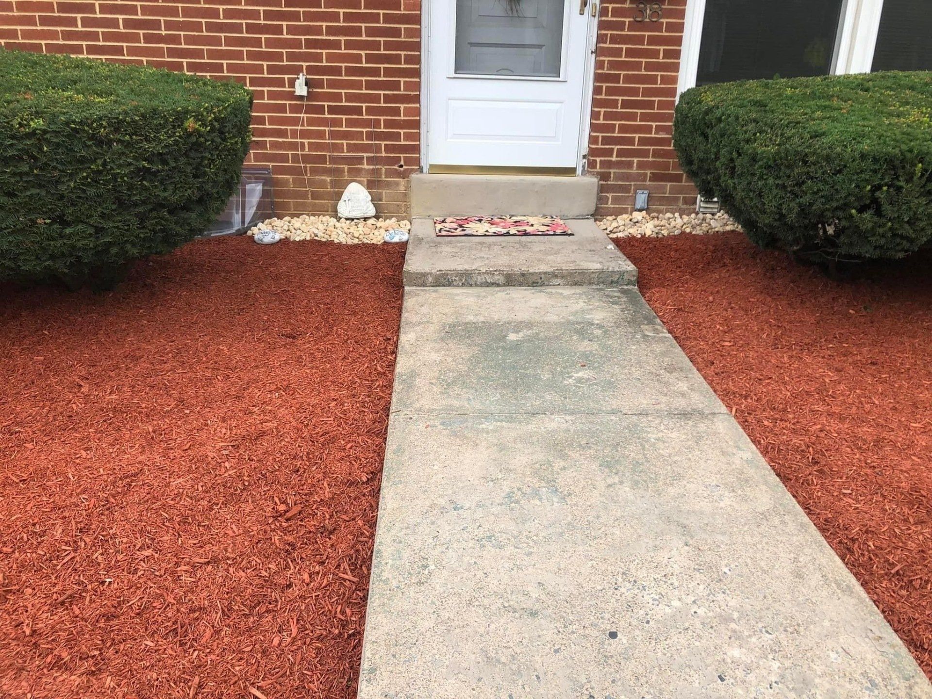 A walkway with red mulch on both sides