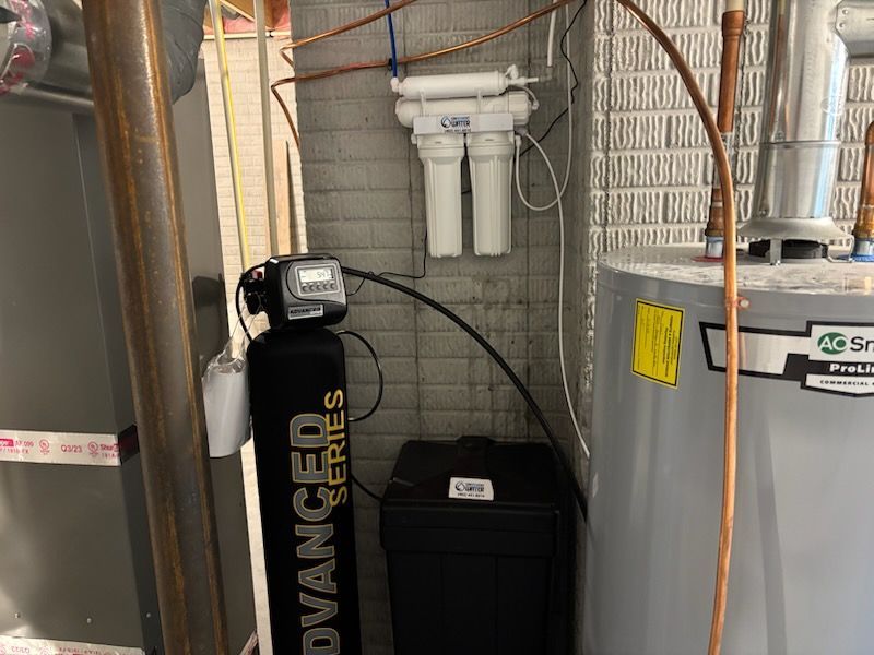 Water treatment system in a utility room with a water softener, filter, and water heater.