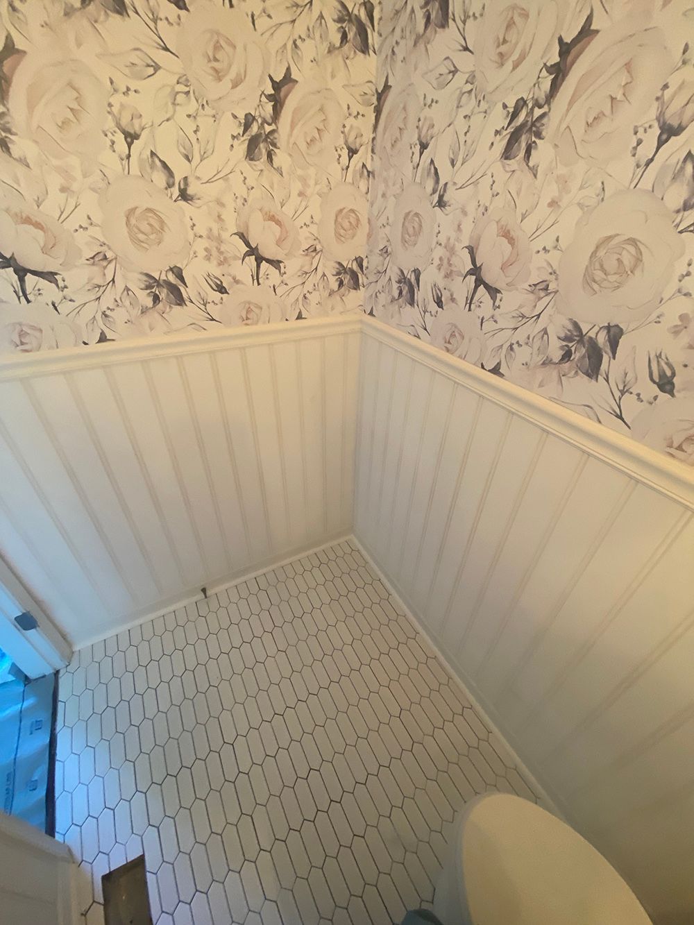 A bathroom with a toilet and a floral wallpaper on the wall.