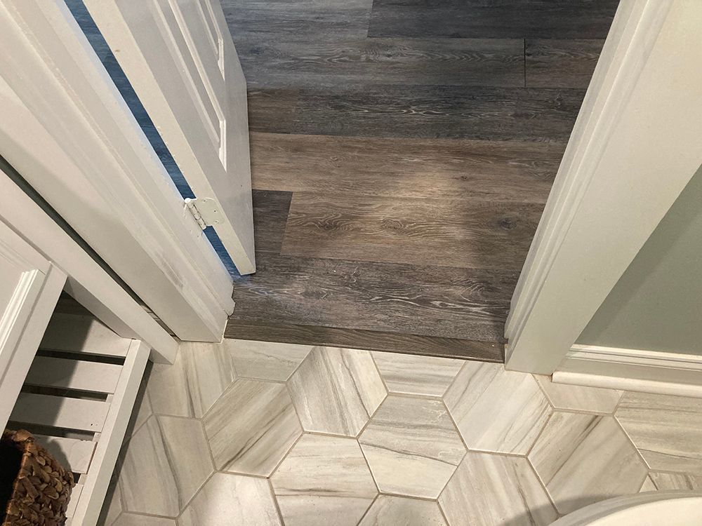 A bathroom with a hexagon tile floor and a wooden floor.