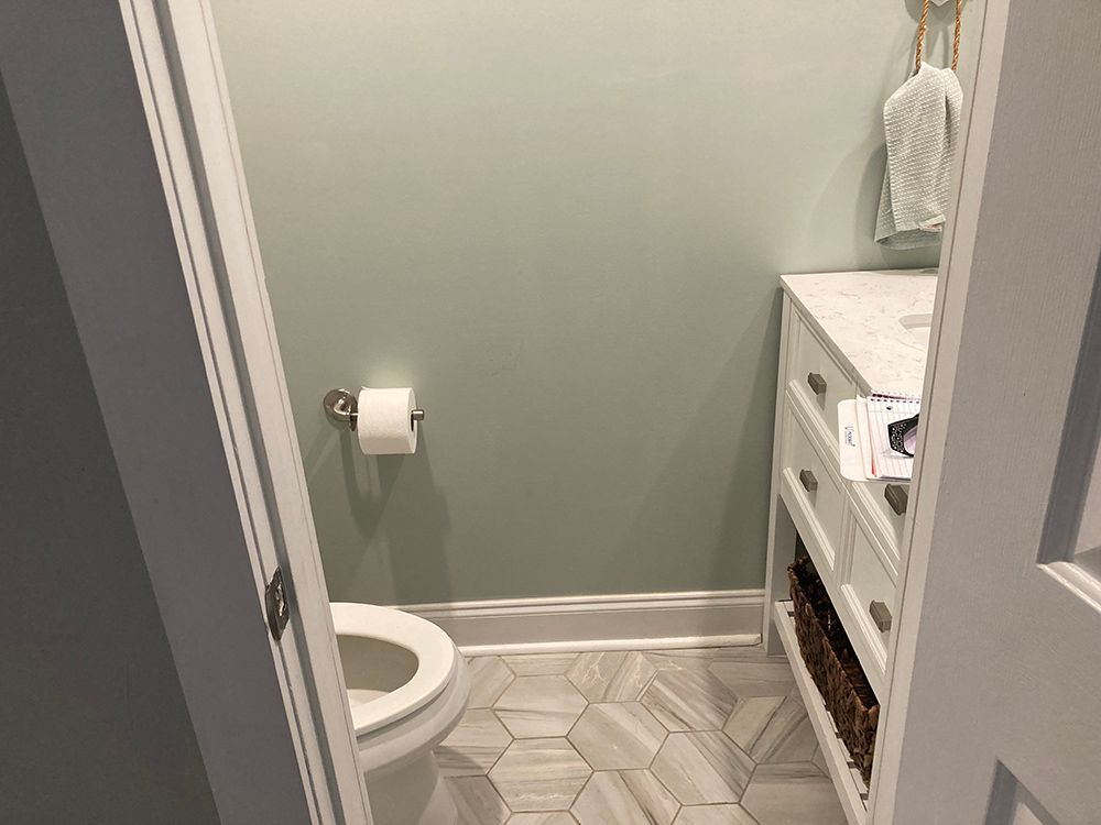 A bathroom with a toilet , sink , and towel rack.