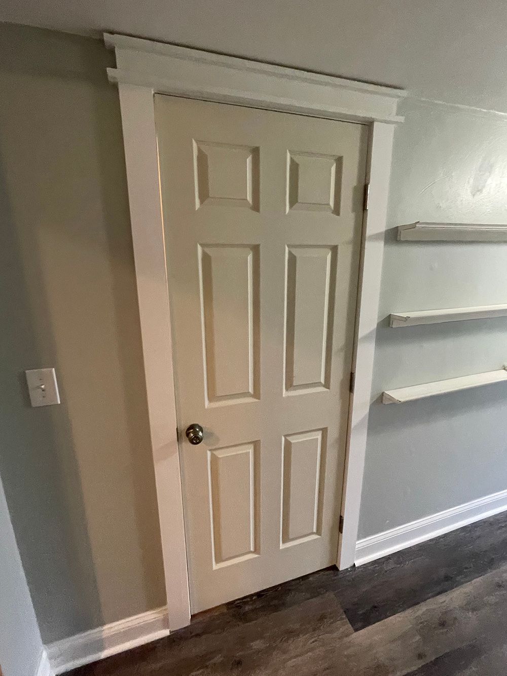 A white door is sitting in a room next to a wall.