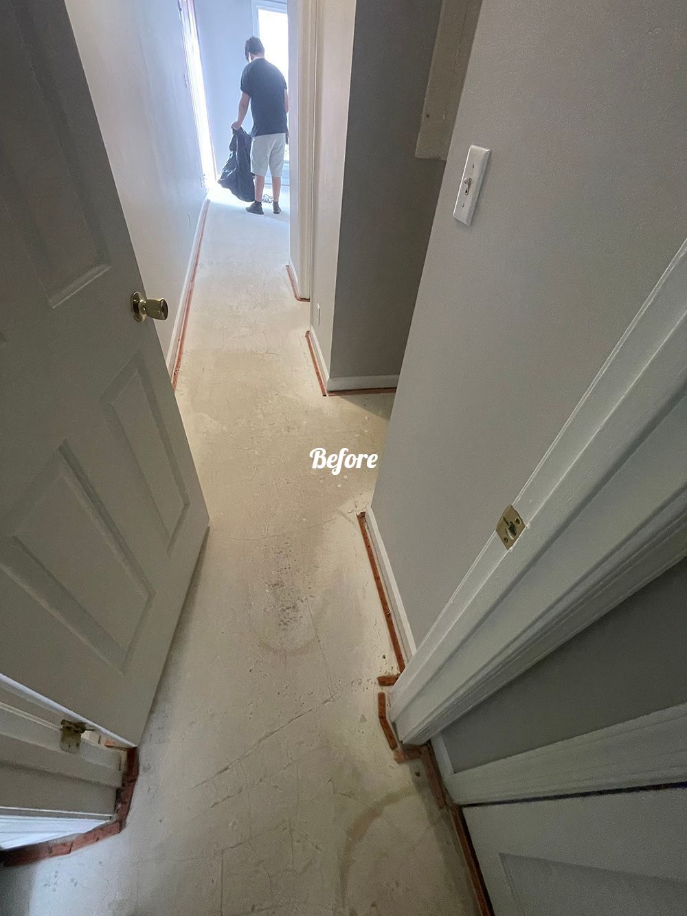 A man is standing in a hallway with a vacuum cleaner.