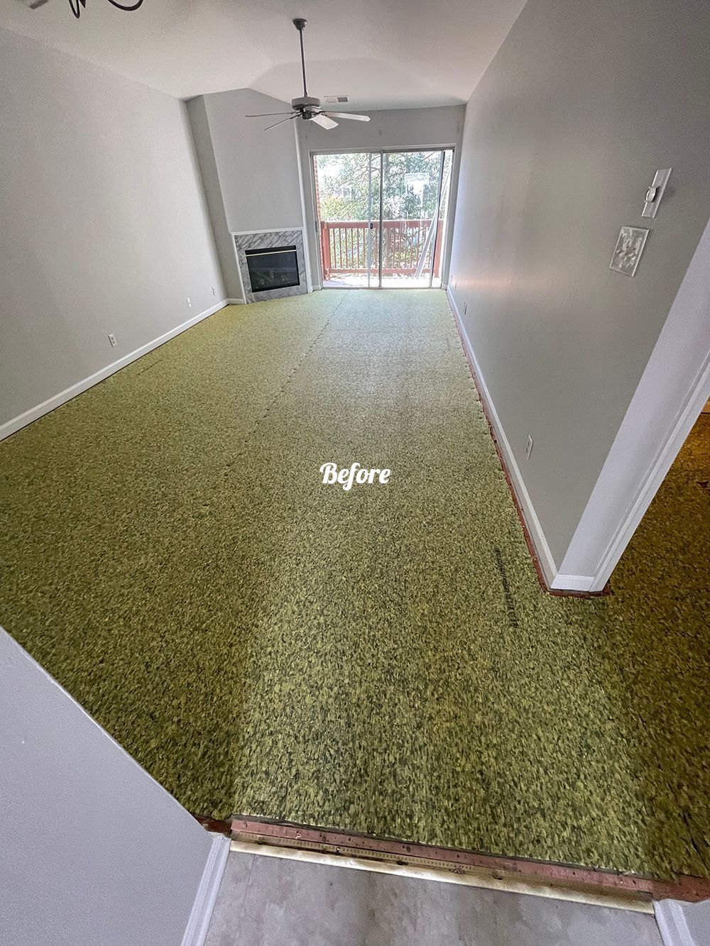 A living room with a green carpet and a ceiling fan.