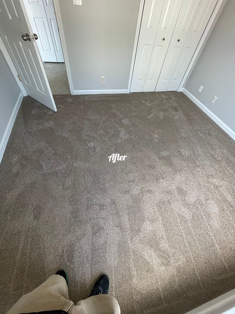 A person is standing in an empty room with a carpeted floor.