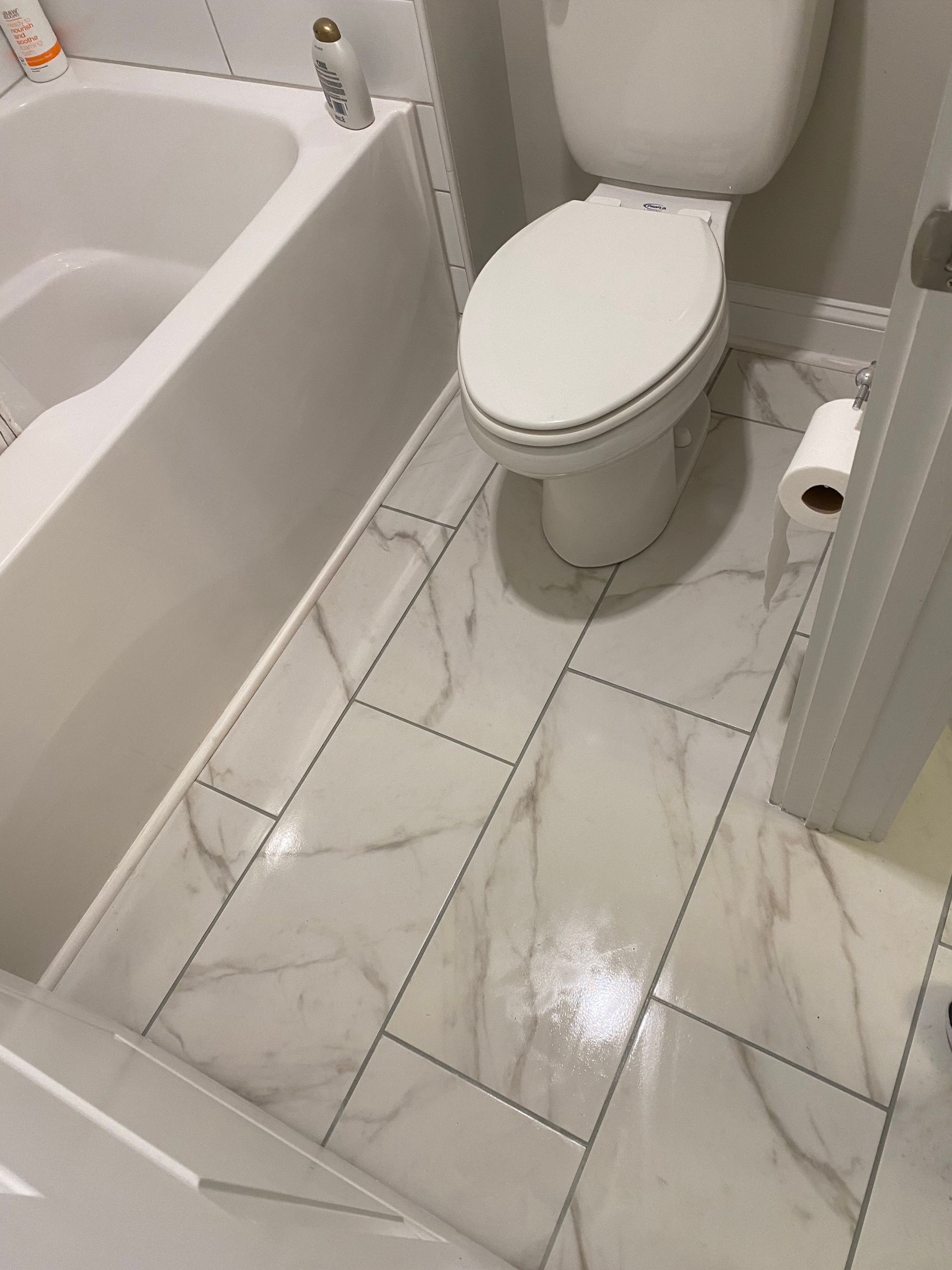 A bathroom with a toilet , tub , and paper towel.