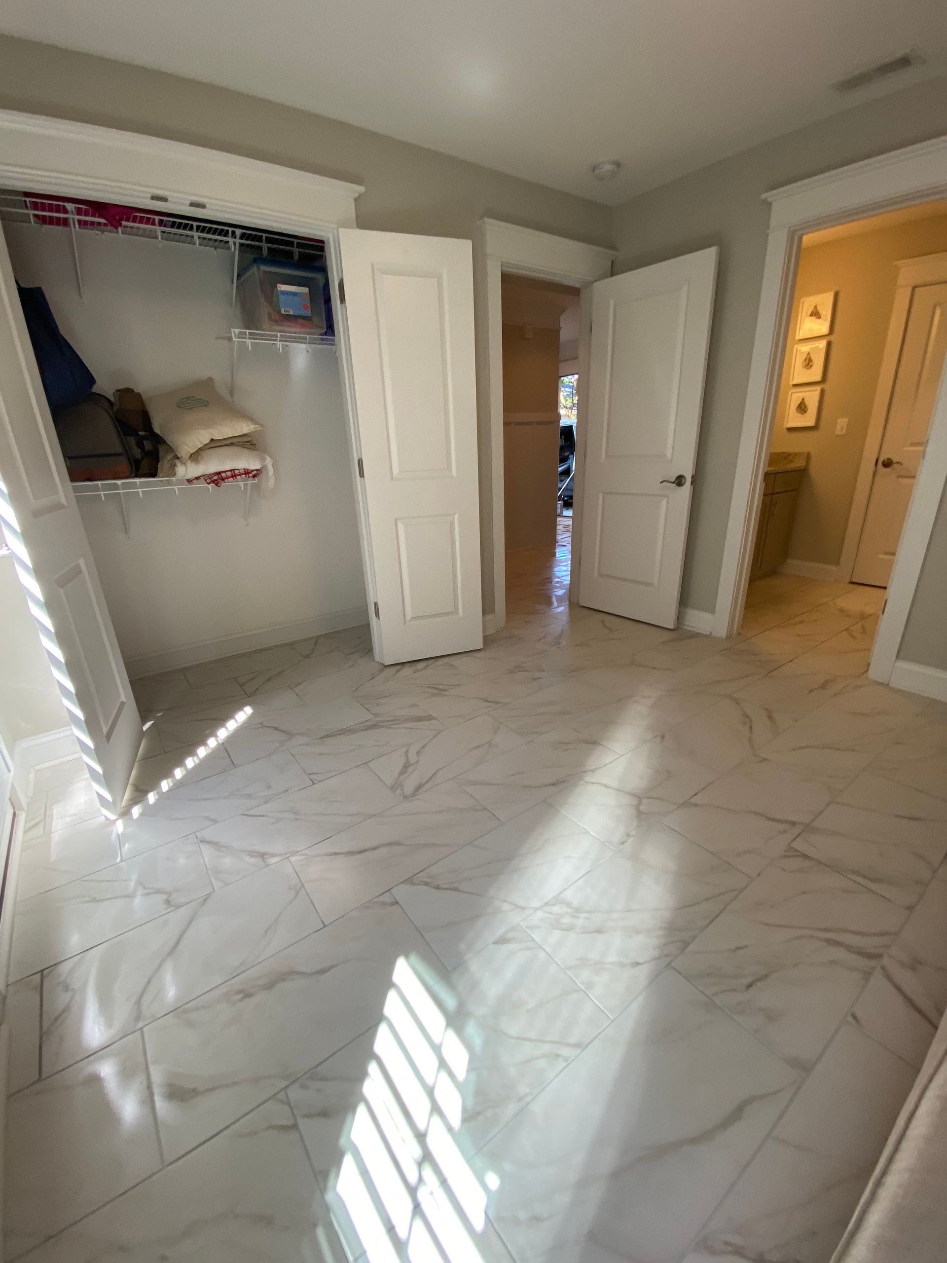 A bedroom with a walk in closet and a tiled floor.