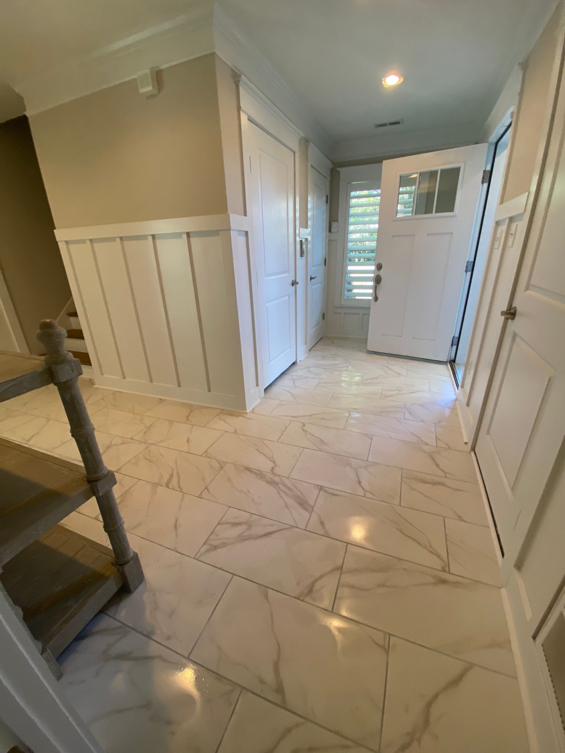 A hallway with white tile floors and a white door.