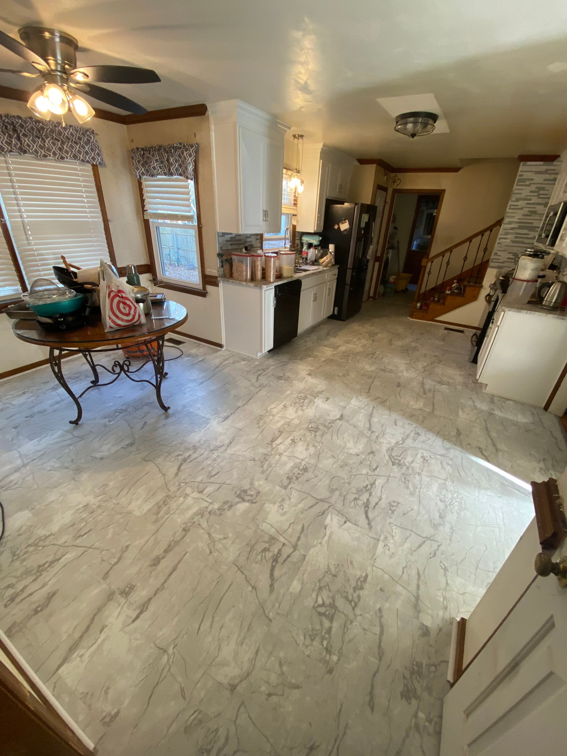 A living room with a table and a ceiling fan.