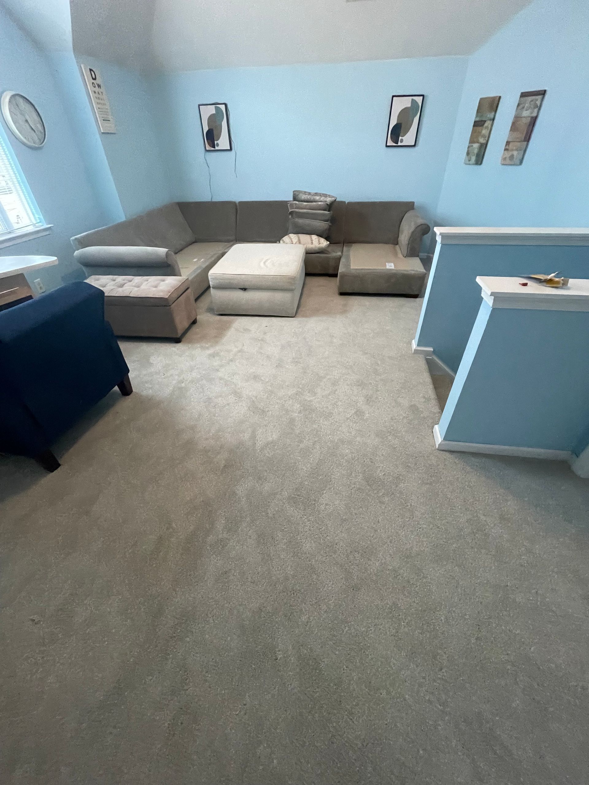 A living room with a large sectional couch and ottoman.