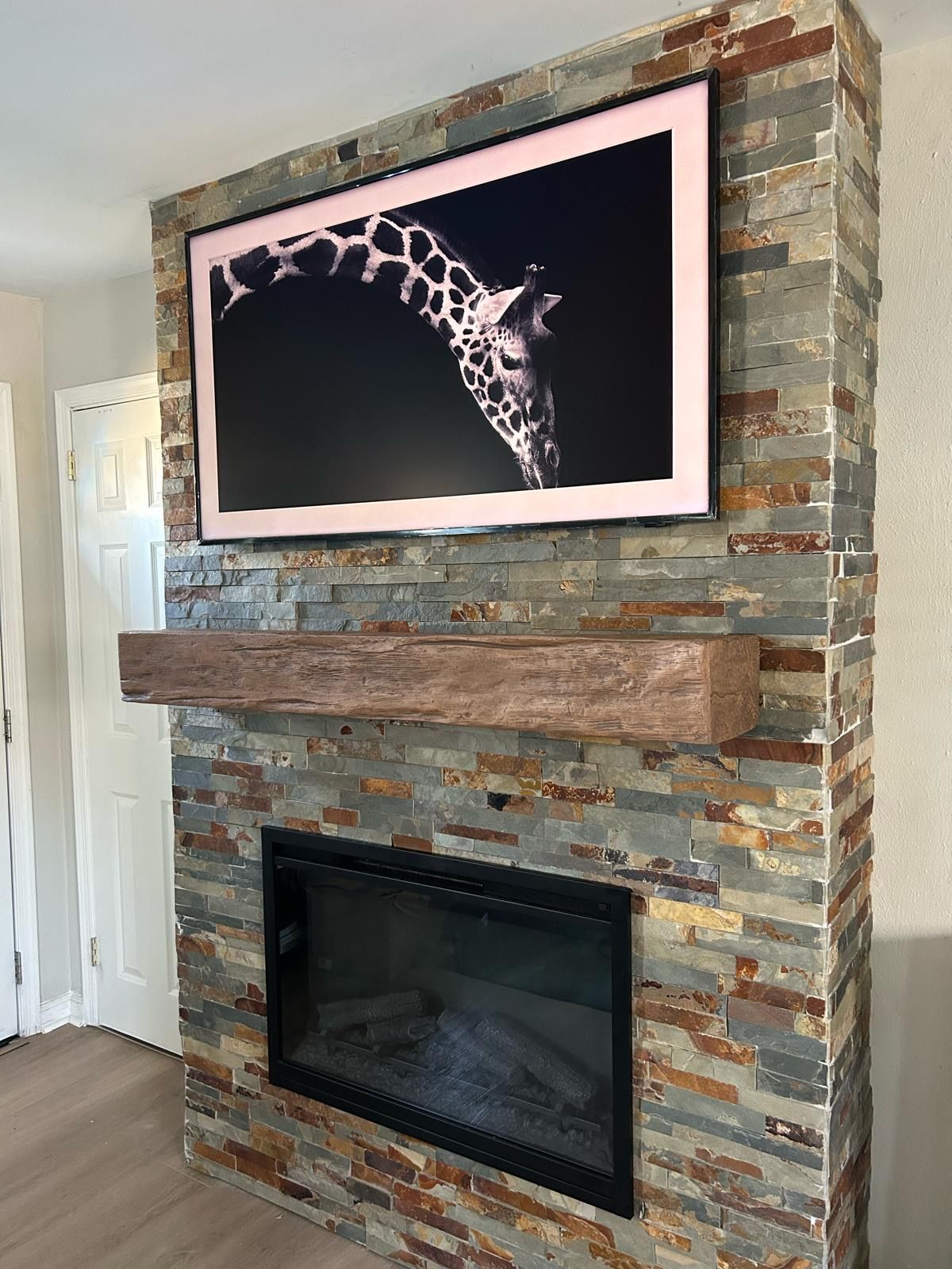 A fireplace with a picture of a giraffe on the wall above it.