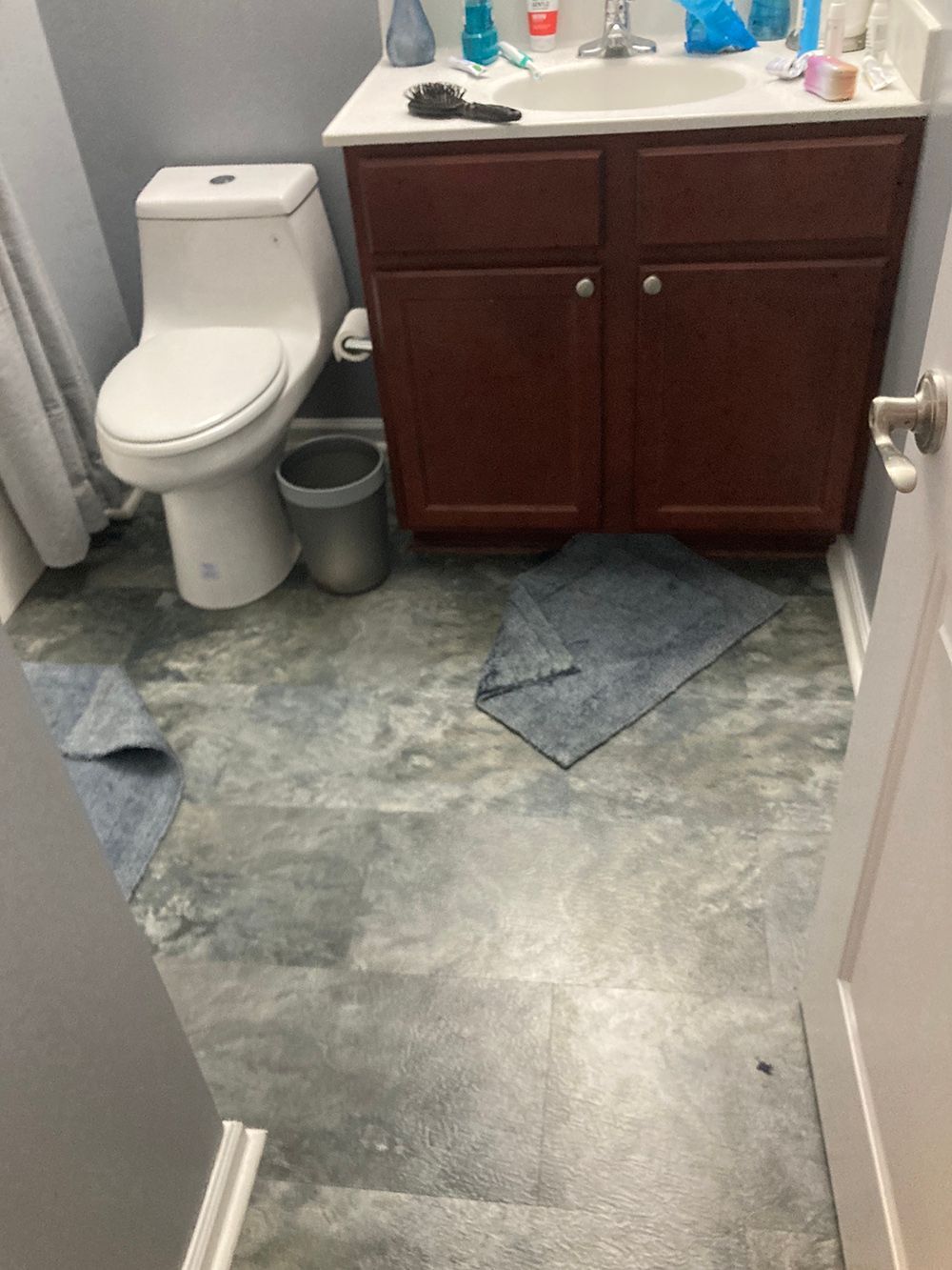 A bathroom with a toilet, sink, and cabinets.