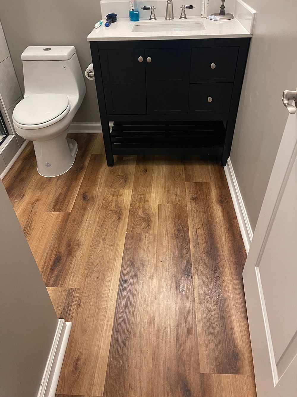 A bathroom with a toilet, sink, and wooden floor.