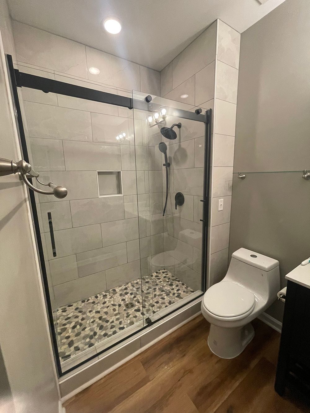 A bathroom with a toilet, sink, shower and glass door.