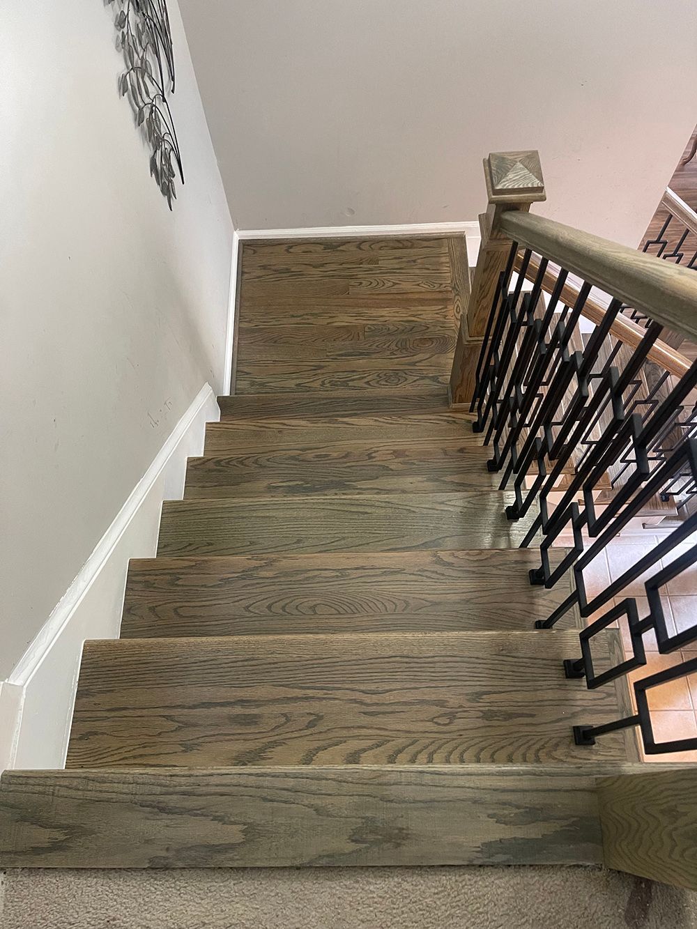 A wooden staircase with a wrought iron railing in a house.