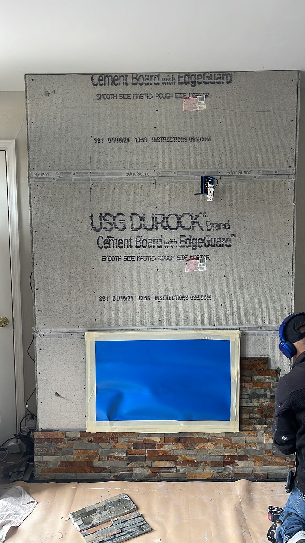 A man is working on a fireplace in a living room.